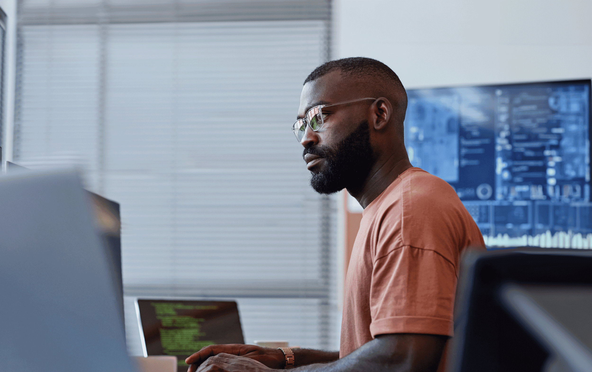 Side view portrait of black software developer using computer in high technology office, data systems and programming