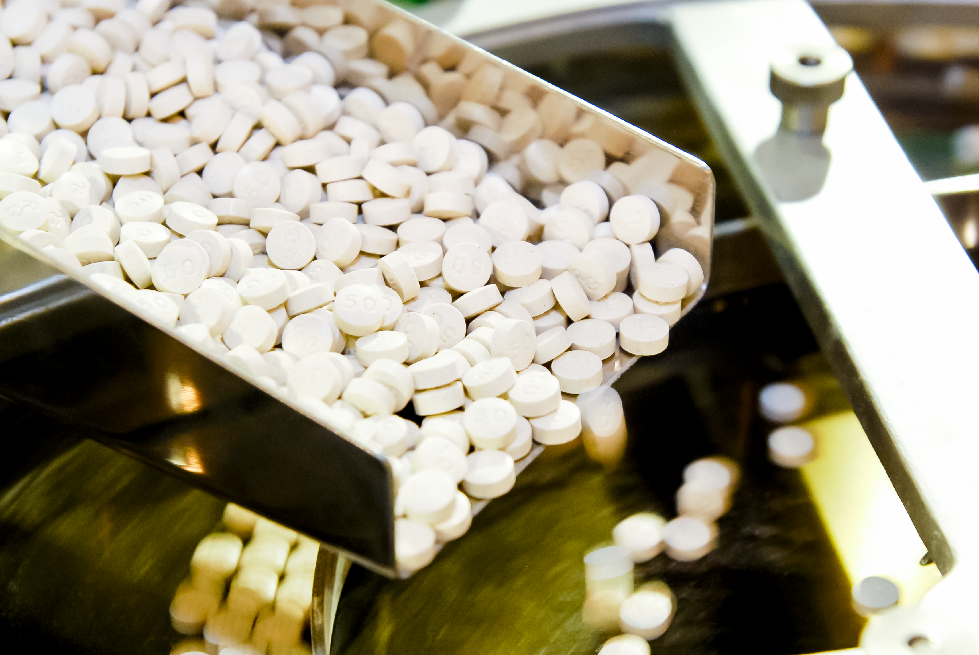 Closeup of pharmaceutical medicine tablet pill production in the rails