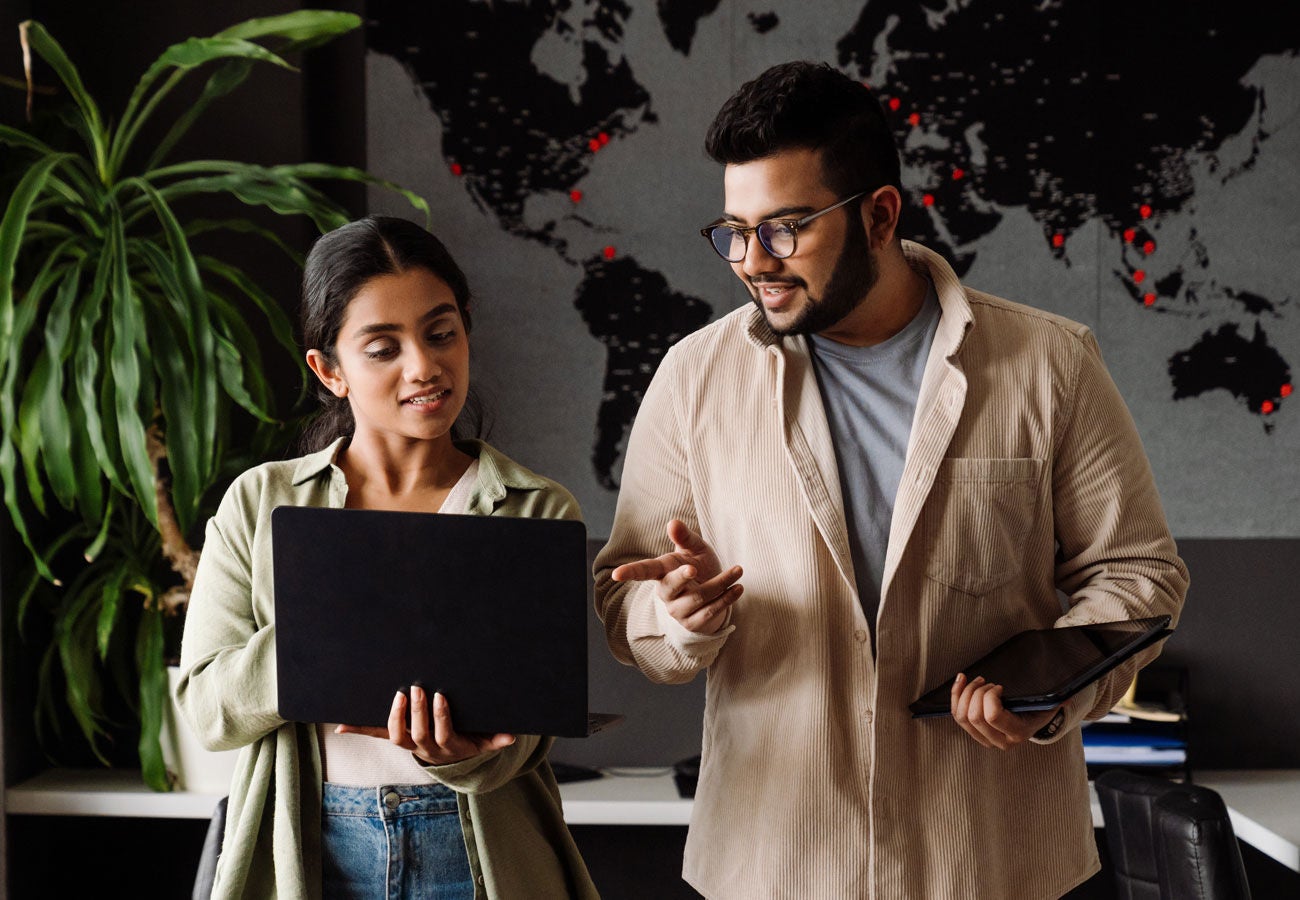 Two people working with a laptop in an office.