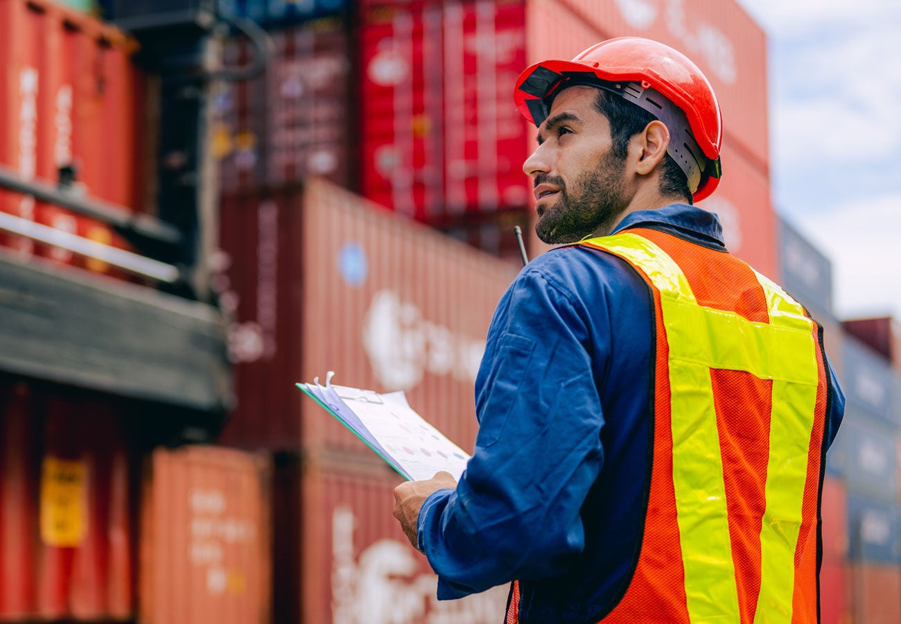 A man works with shipping containers at a seaport.