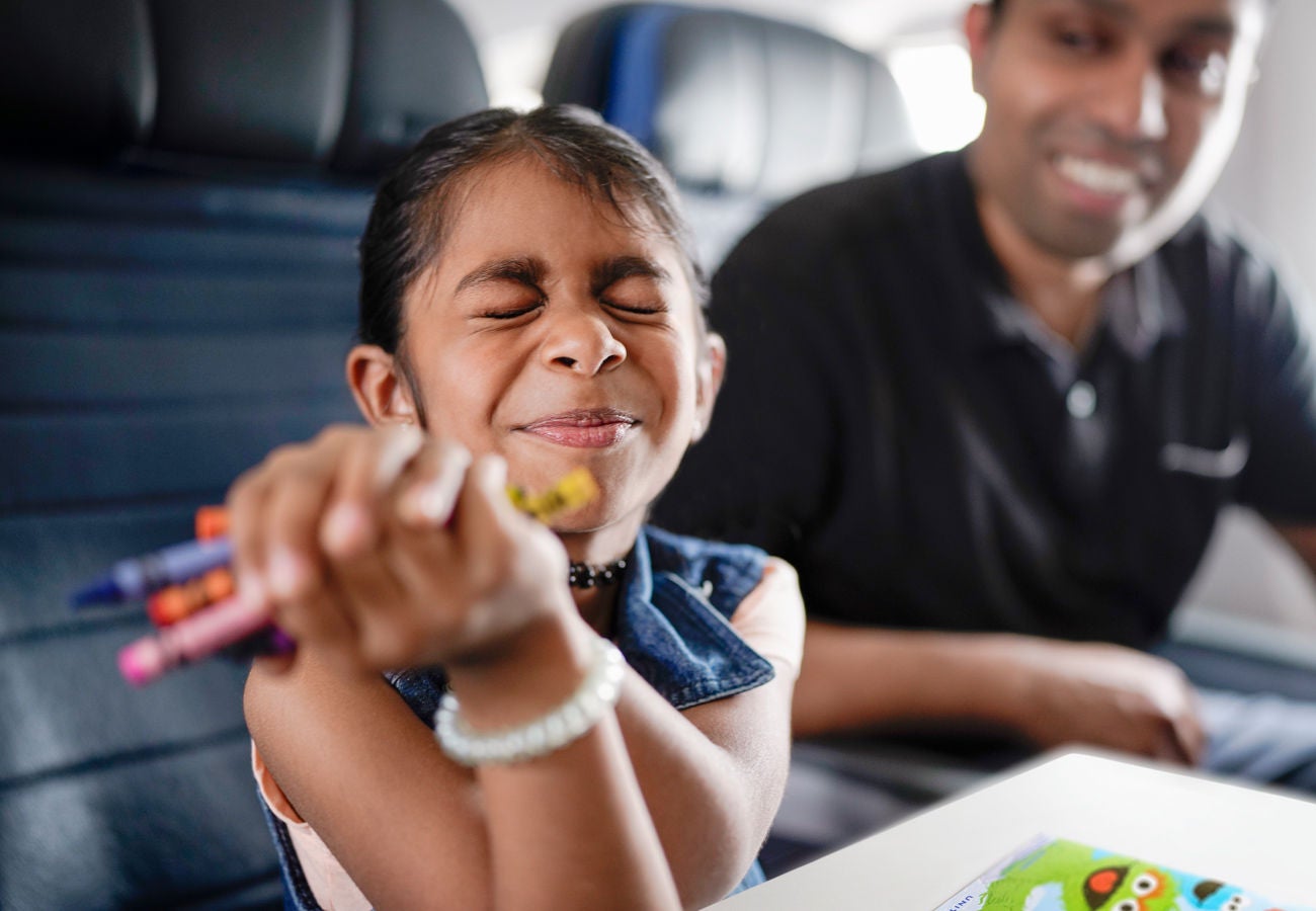 A happy girl colors at her seat while on a United Airlines flight.