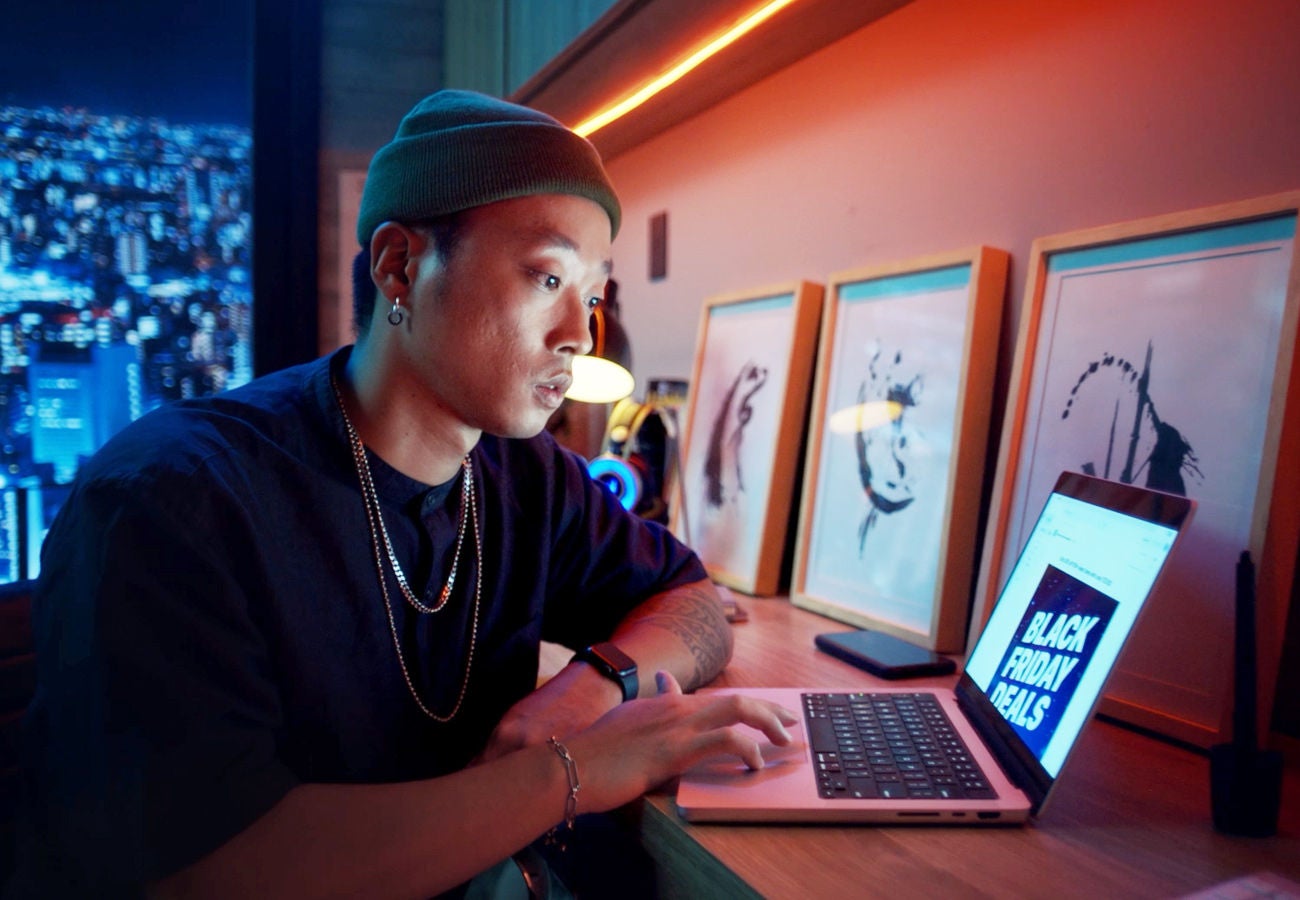 A man is using a laptop computer displaying a promotional email.