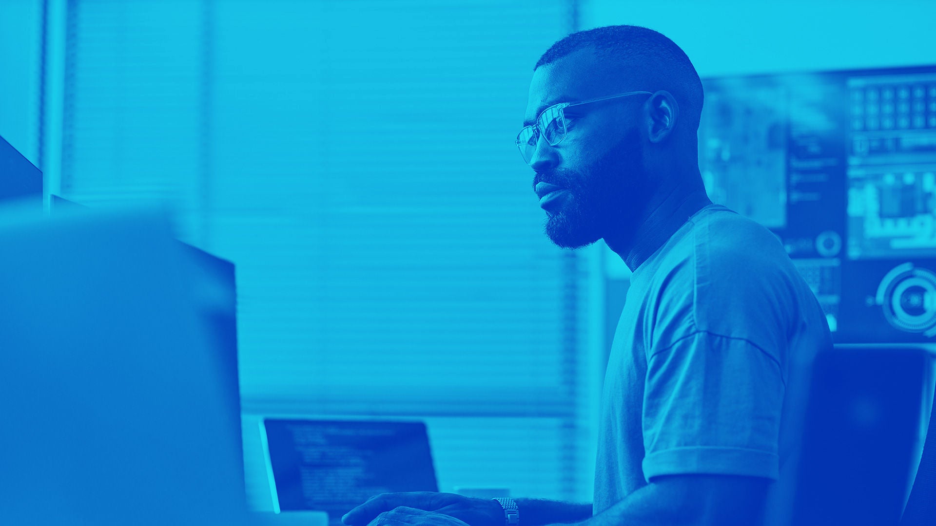 Side view portrait of black software developer using computer in high technology office, data systems and programming