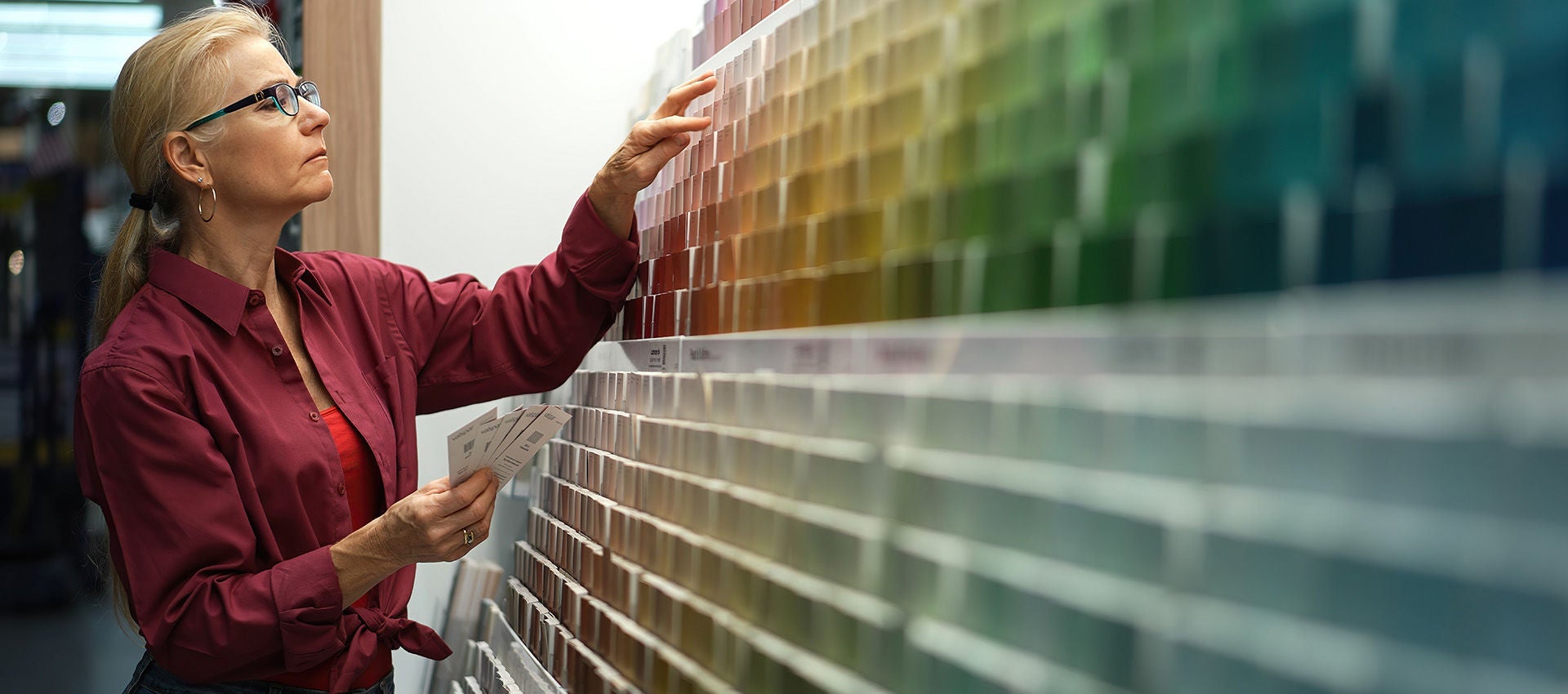 A woman is looking at paint swatches at a hardware store