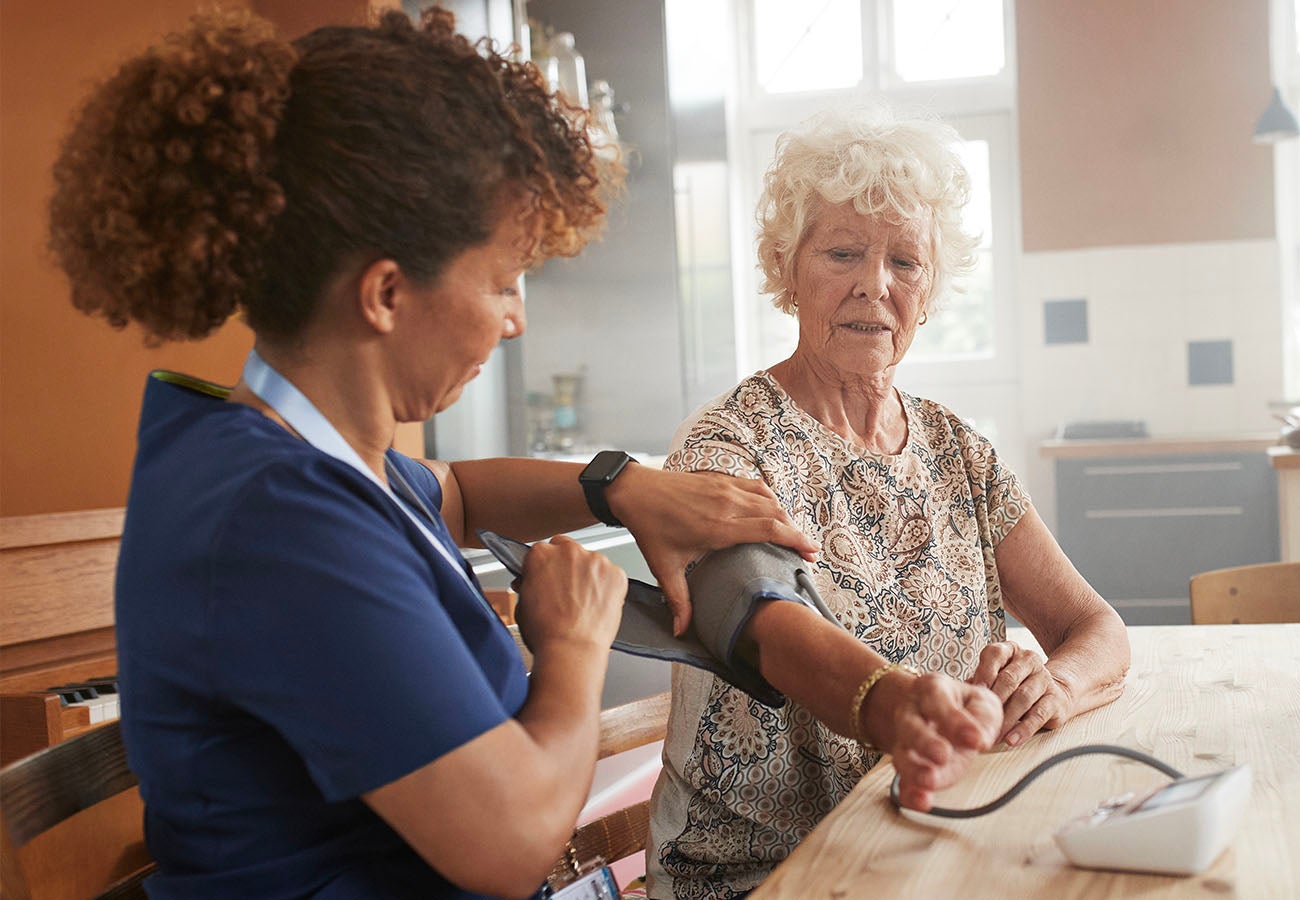 Caregiver taking blood pressure of patient in home