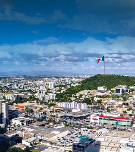 The flag of Mexico flies over Monterrey on a sunny day.