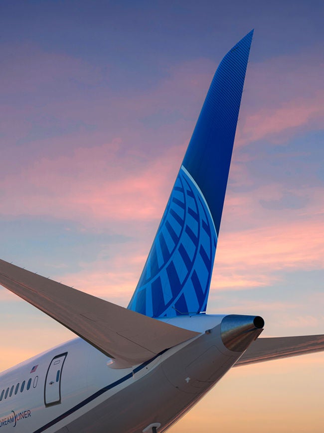 A United Airlines plane tail stands tall with a colorful sunset.