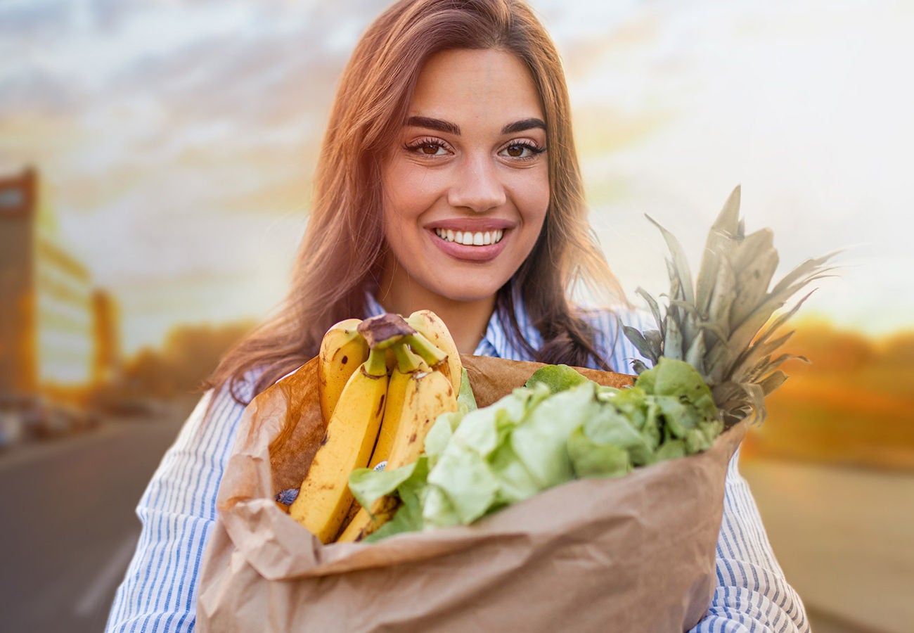 A woman holds a bag of groceries.