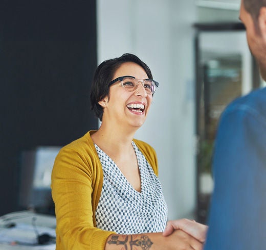 A woman laughs with a colleague in the office of a company.