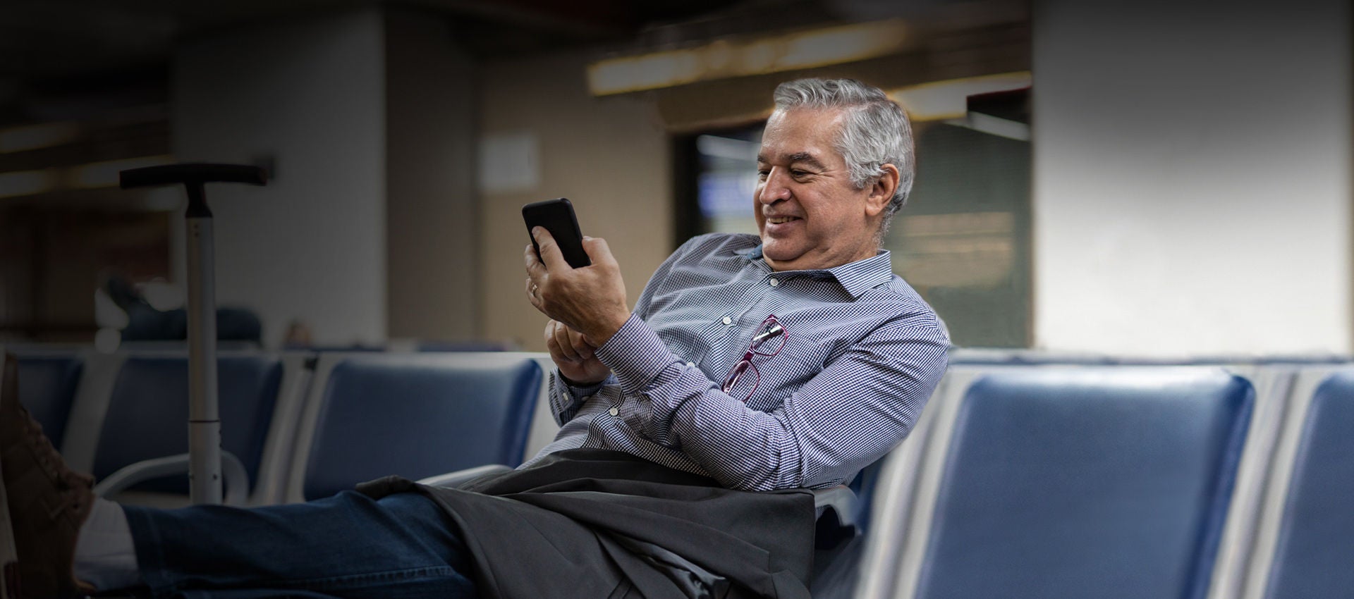 A delighted customer uses his mobile device while waiting at the gate in an airport. 