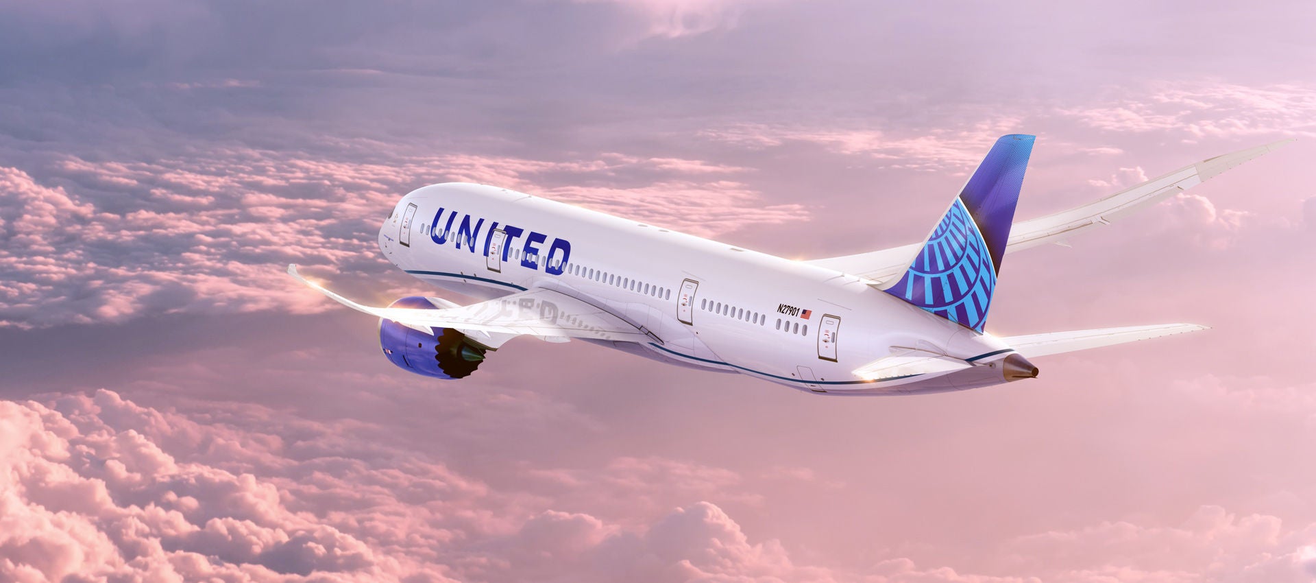 A United Airlines Boeing 787 Dreamliner soars in the sky though an incredible cotton candy pink sunset. 