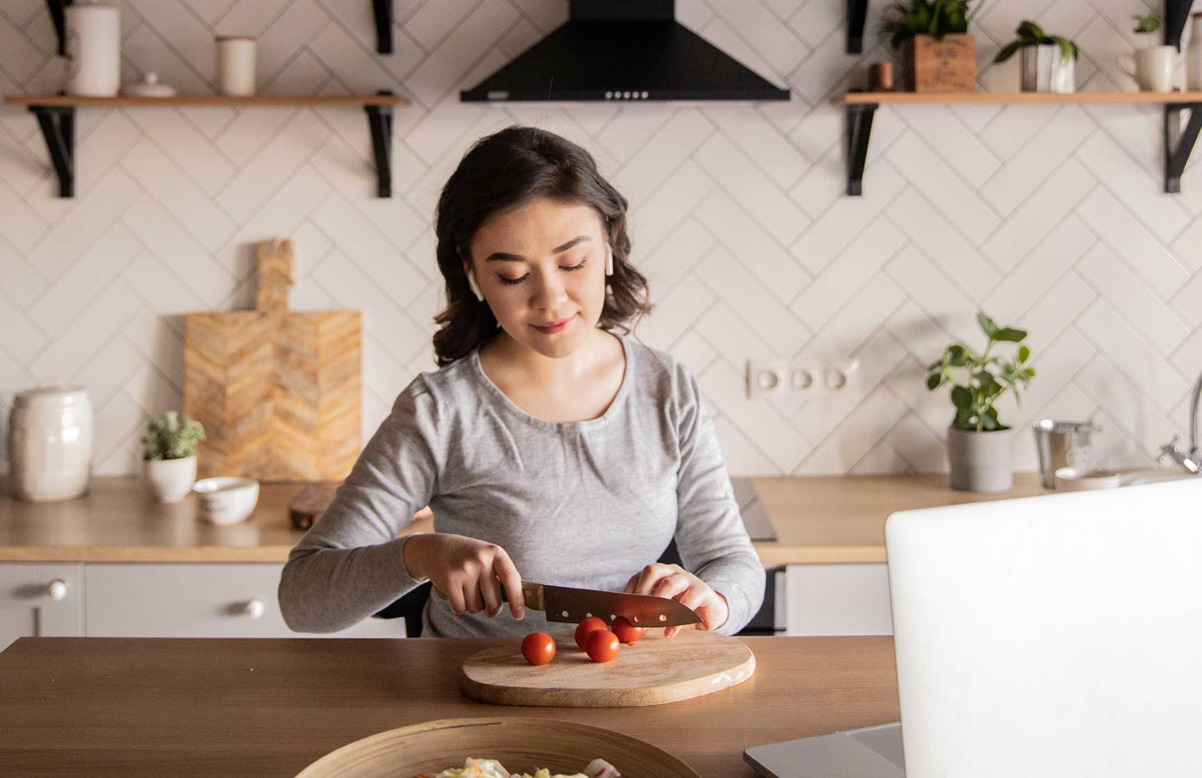 Woman in kitchen cutting tomatoes 